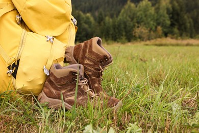 Photo of Trekking shoes and camping tent on green grass outdoors, space for text