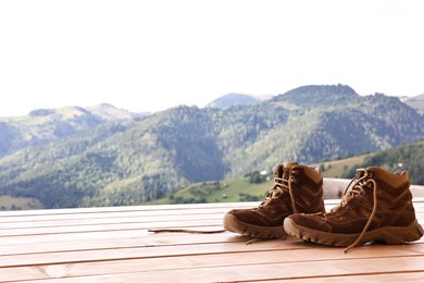 Trekking shoes on wooden table, space for text