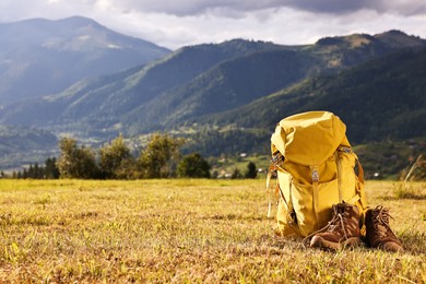 Photo of Backpack and trekking shoes on grass outdoors, space for text