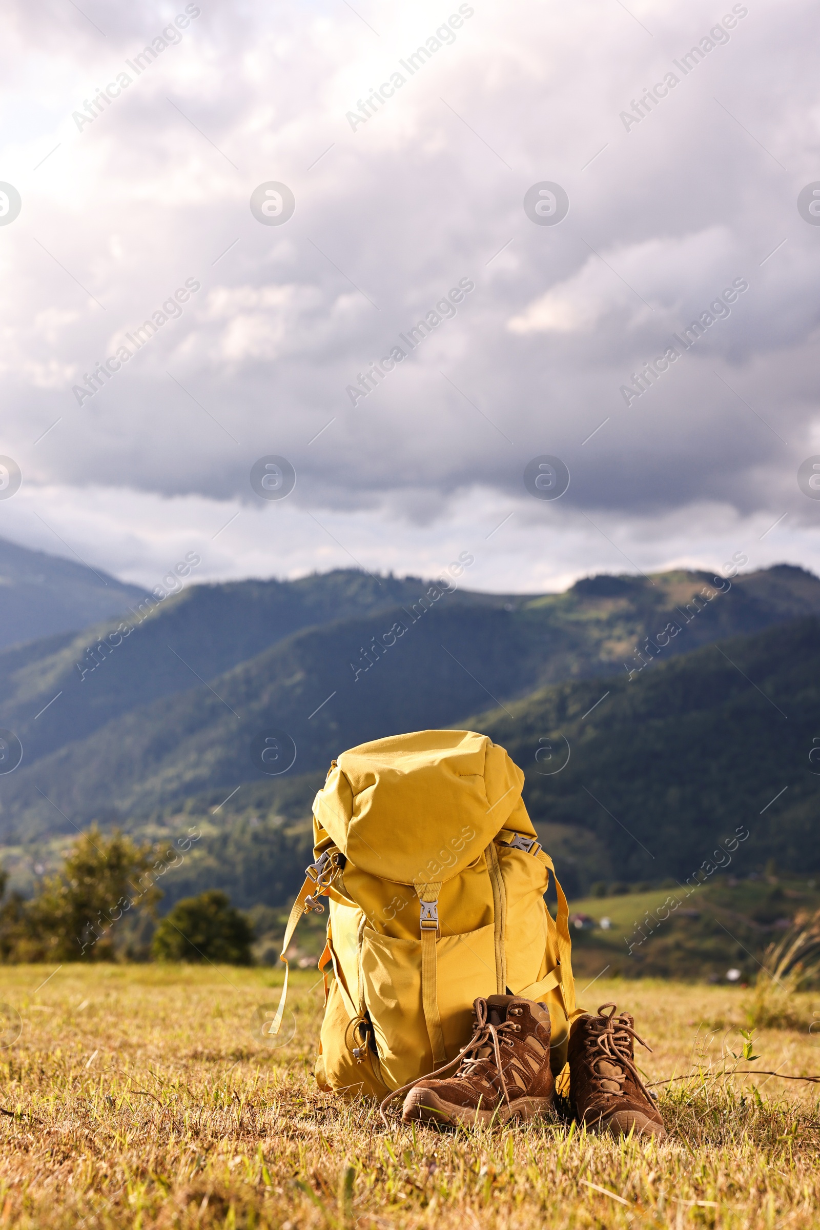 Photo of Backpack and trekking shoes on grass outdoors, space for text