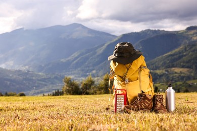 Backpack, trekking shoes and other camping equipment on grass outdoors, space for text