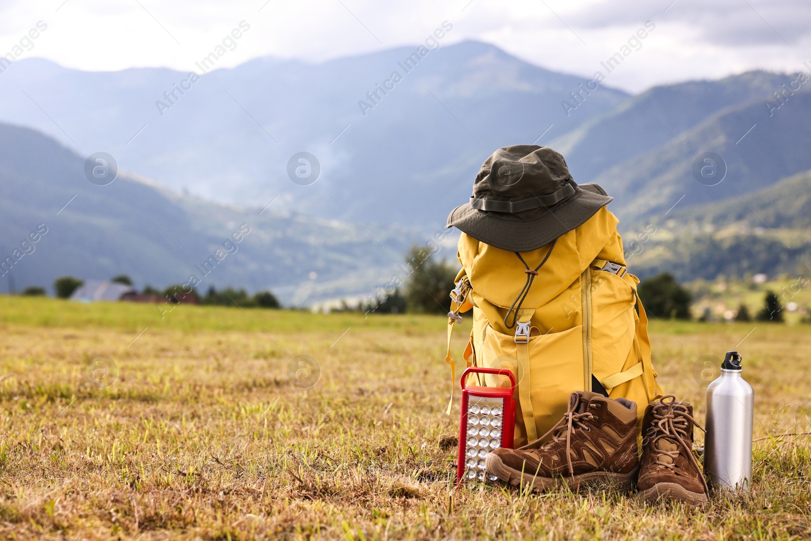 Photo of Backpack, trekking shoes and other camping equipment on grass outdoors, space for text