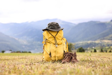 Backpack, hat and trekking shoes on grass outdoors