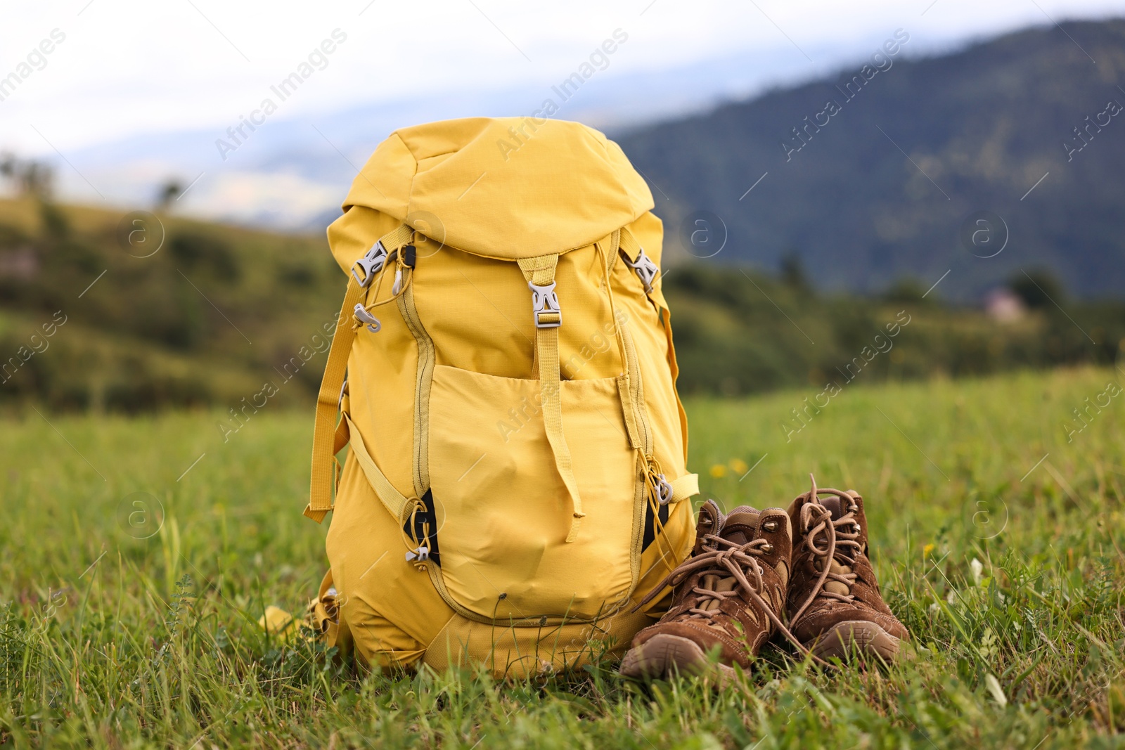 Photo of Backpack and trekking shoes on green grass outdoors