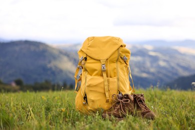 Photo of Backpack and trekking shoes on green grass outdoors