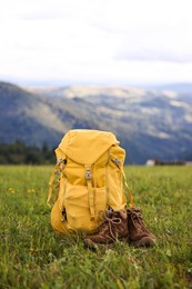 Backpack and trekking shoes on green grass outdoors