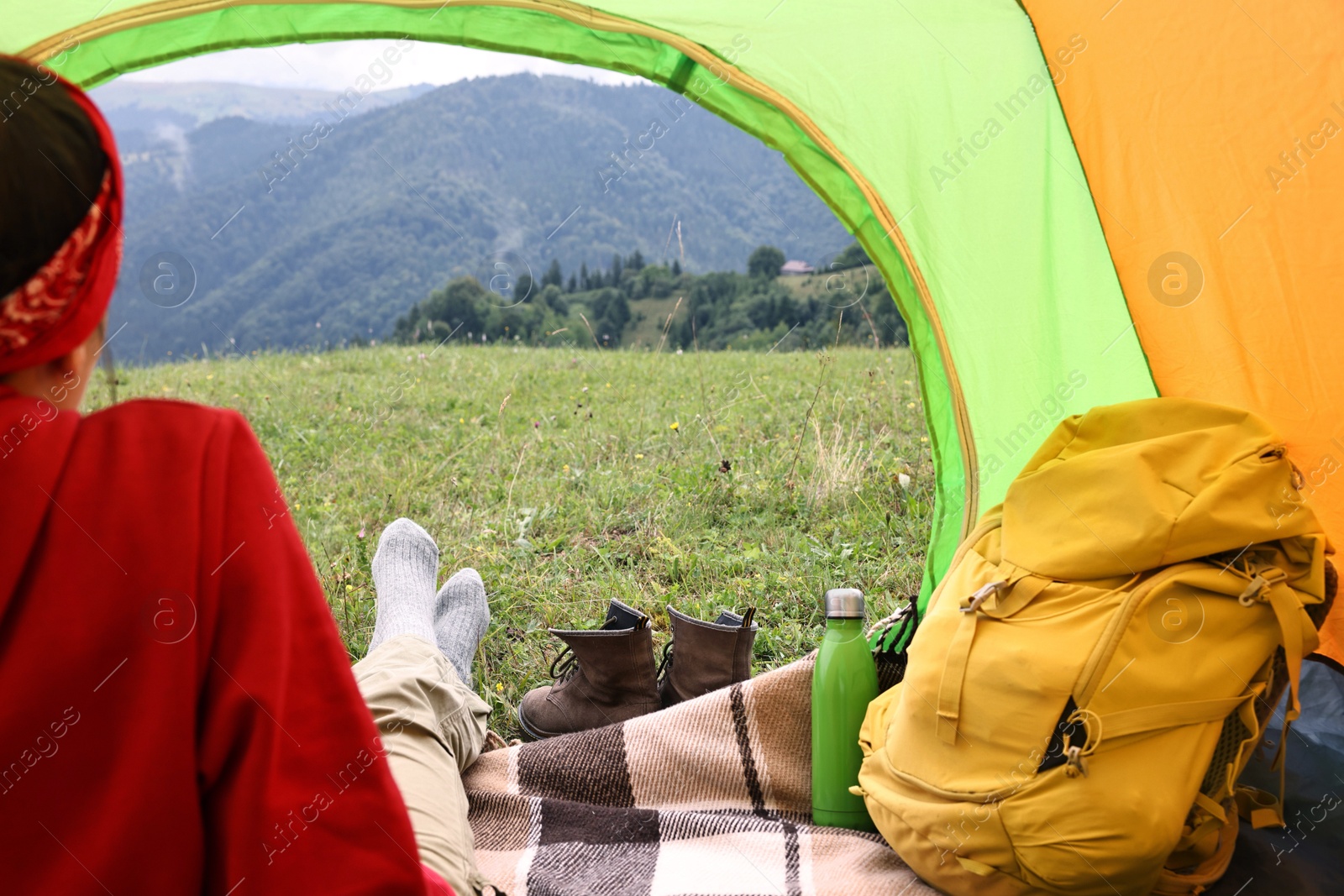 Photo of Woman sitting in tent and looking at beautiful mountains outdoors