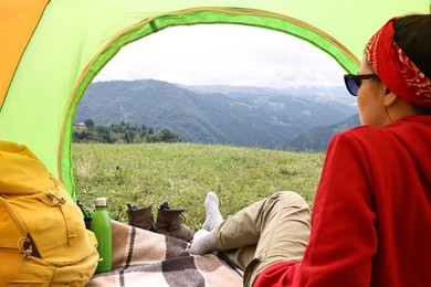 Woman sitting in tent and looking at beautiful mountains outdoors