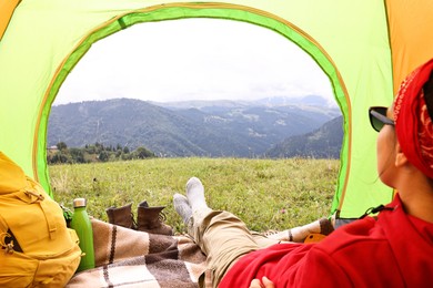 Woman sitting in tent and looking at beautiful mountains outdoors