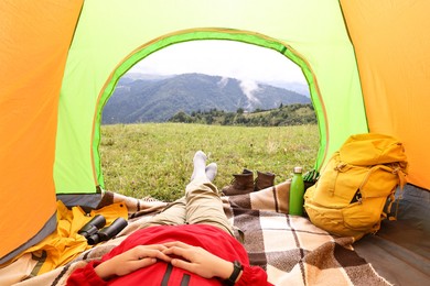 Woman lying in tent outdoors, closeup view