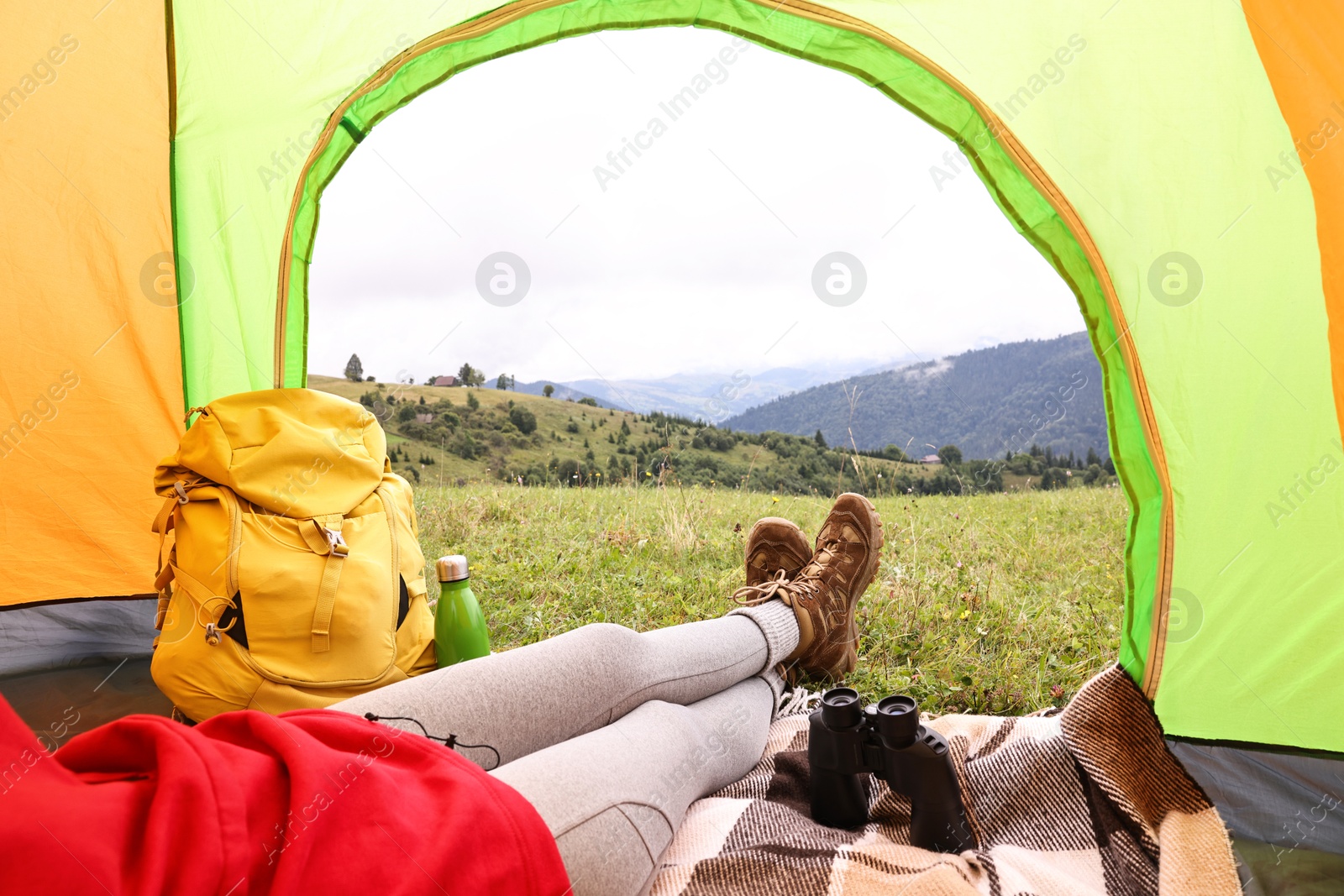 Photo of Woman wearing trekking shoes and lying in tent outdoors, closeup