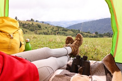 Woman wearing trekking shoes and lying in tent outdoors, closeup