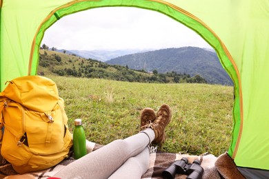 Woman wearing trekking shoes and lying in tent outdoors, closeup