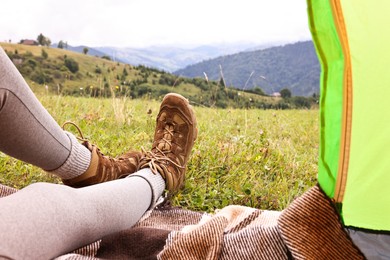 Photo of Woman wearing trekking shoes and lying in tent outdoors, closeup