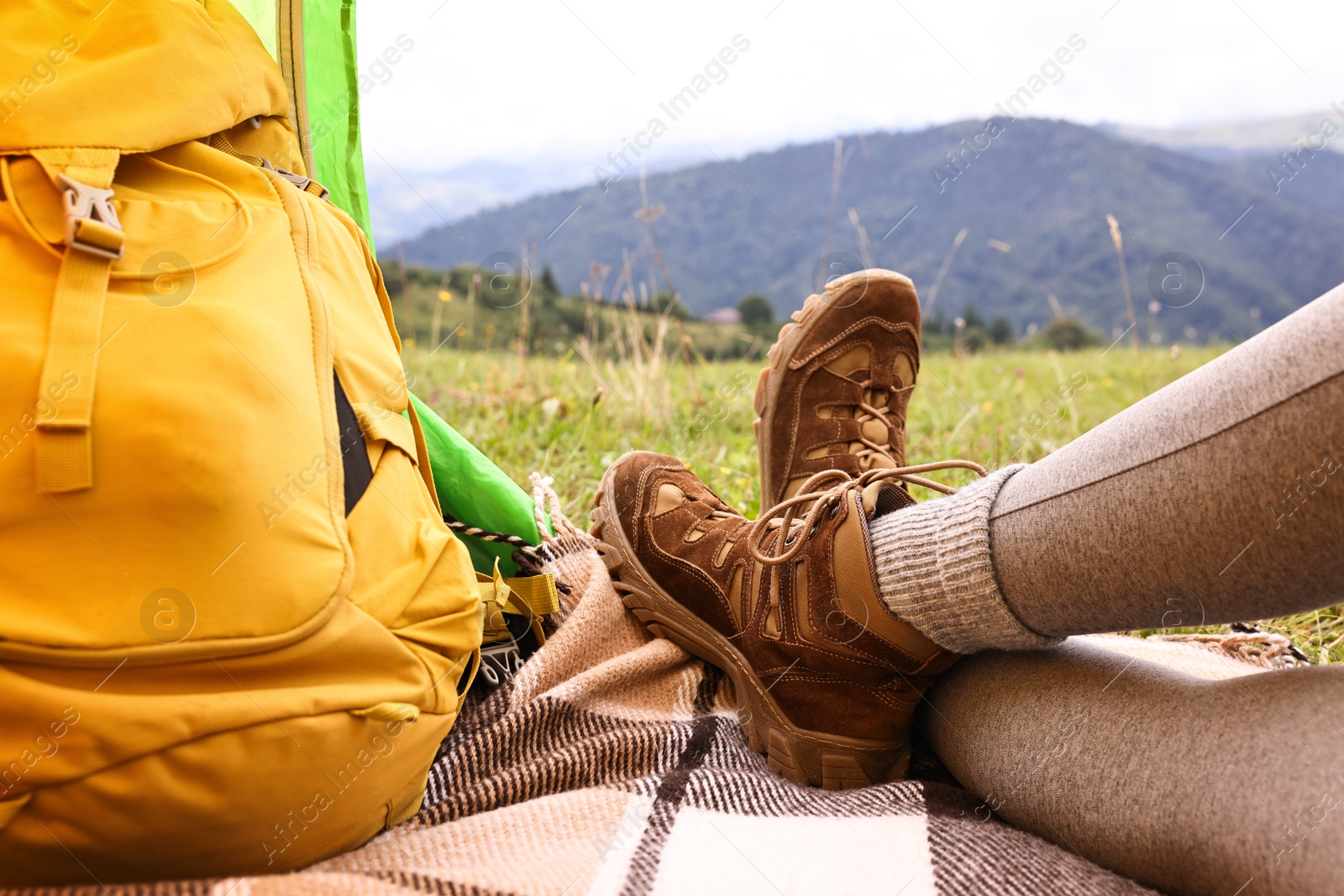 Photo of Woman wearing trekking shoes and lying in tent outdoors, closeup