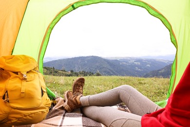 Photo of Woman wearing trekking shoes and lying in tent outdoors, closeup