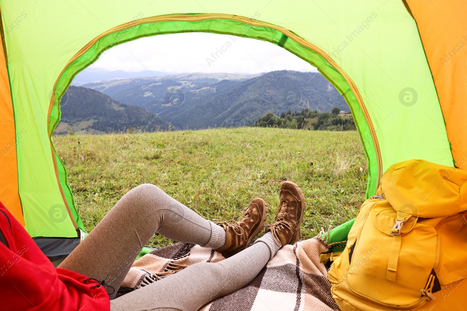 Photo of Woman wearing trekking shoes and lying in tent outdoors, closeup