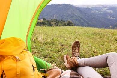 Photo of Woman wearing trekking shoes and lying in tent outdoors, closeup