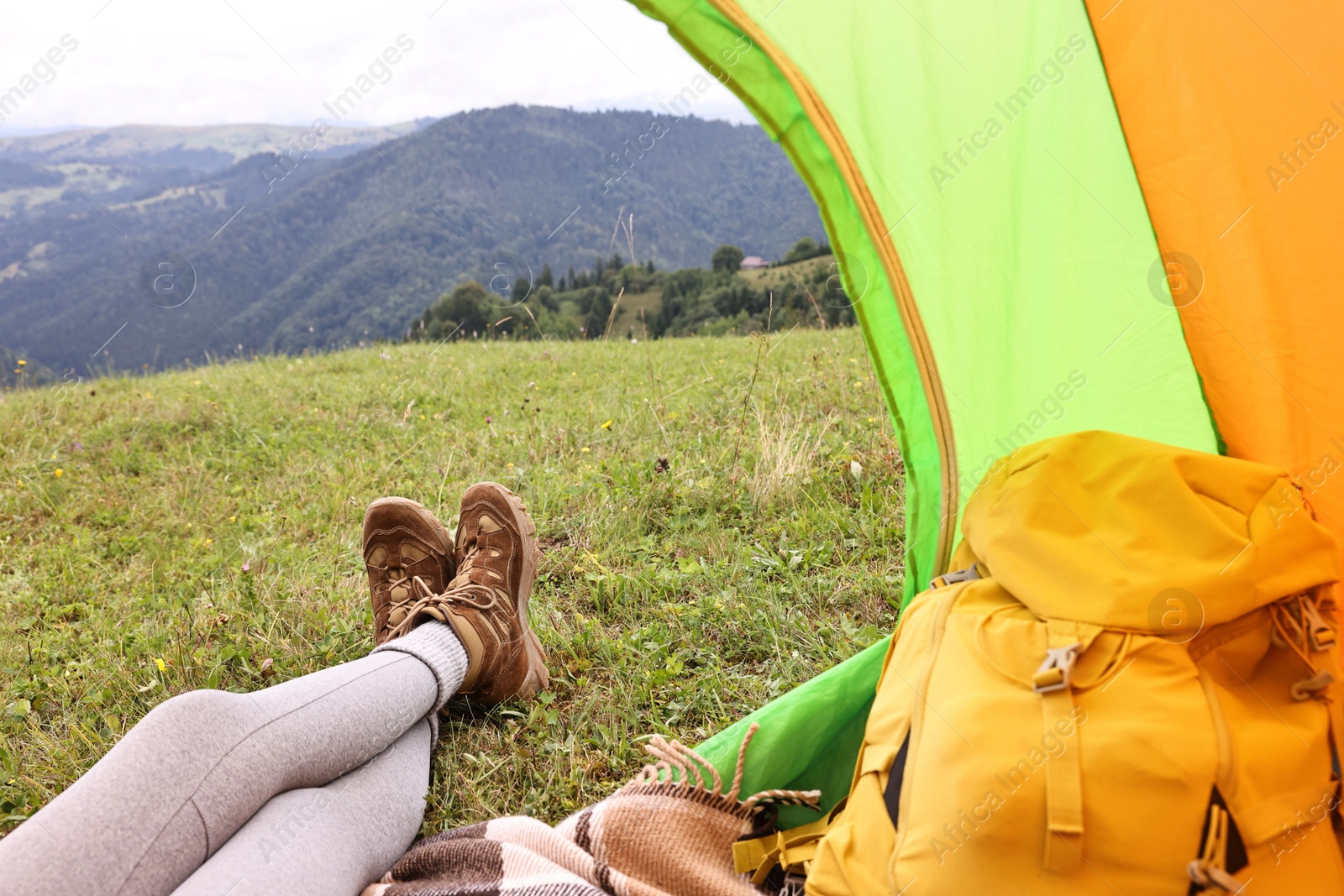 Photo of Woman wearing trekking shoes and lying in tent outdoors, closeup