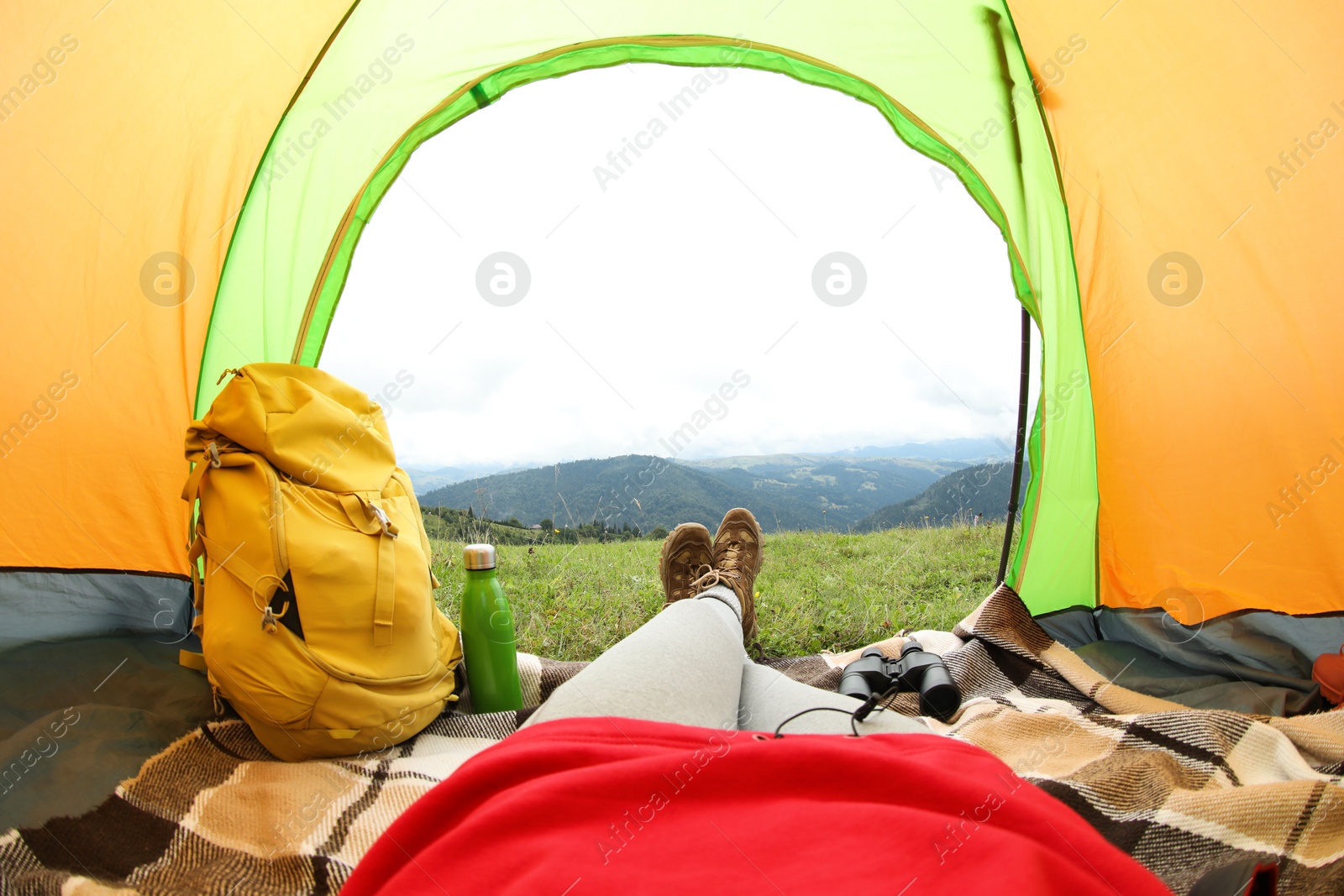 Photo of Woman wearing trekking shoes and lying in tent outdoors, closeup. Fisheye lens effect