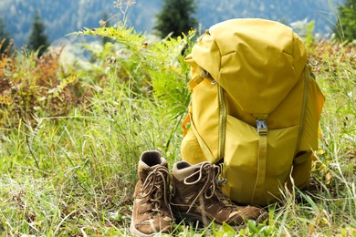 Photo of Backpack and trekking shoes on green grass outdoors