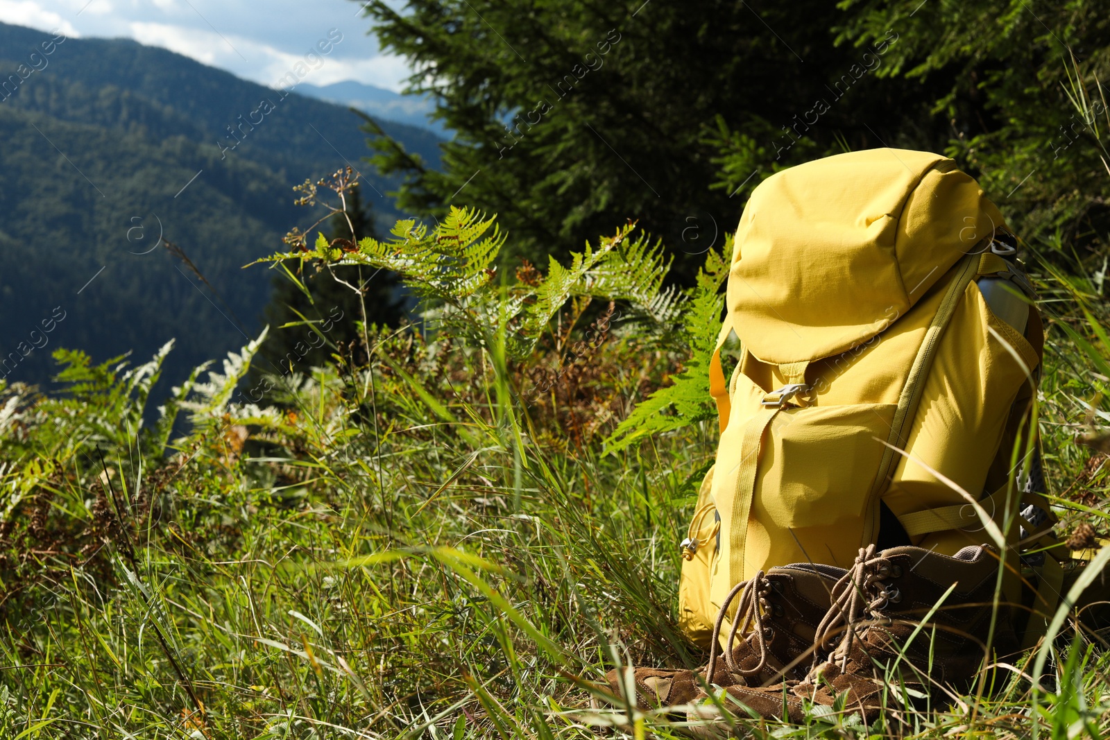 Photo of Backpack and trekking shoes on green grass outdoors