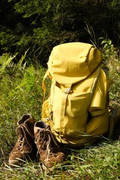 Backpack and trekking shoes on green grass outdoors