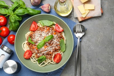 Photo of Delicious pasta bolognese with basil and tomatoes served on grey table, flat lay