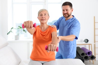 Photo of Senior patient exercising under physiotherapist supervision in rehabilitation center