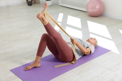 Rehabilitation. Senior woman doing exercise with elastic band indoors