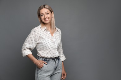 Portrait of beautiful smiling woman on grey background, space for text