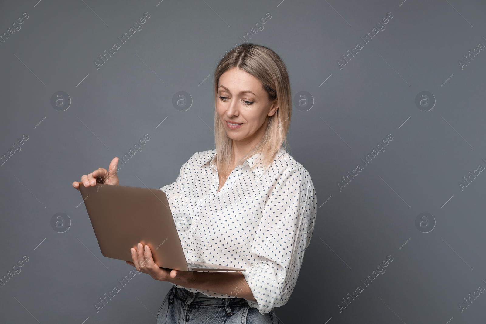 Photo of Beautiful woman with laptop on grey background