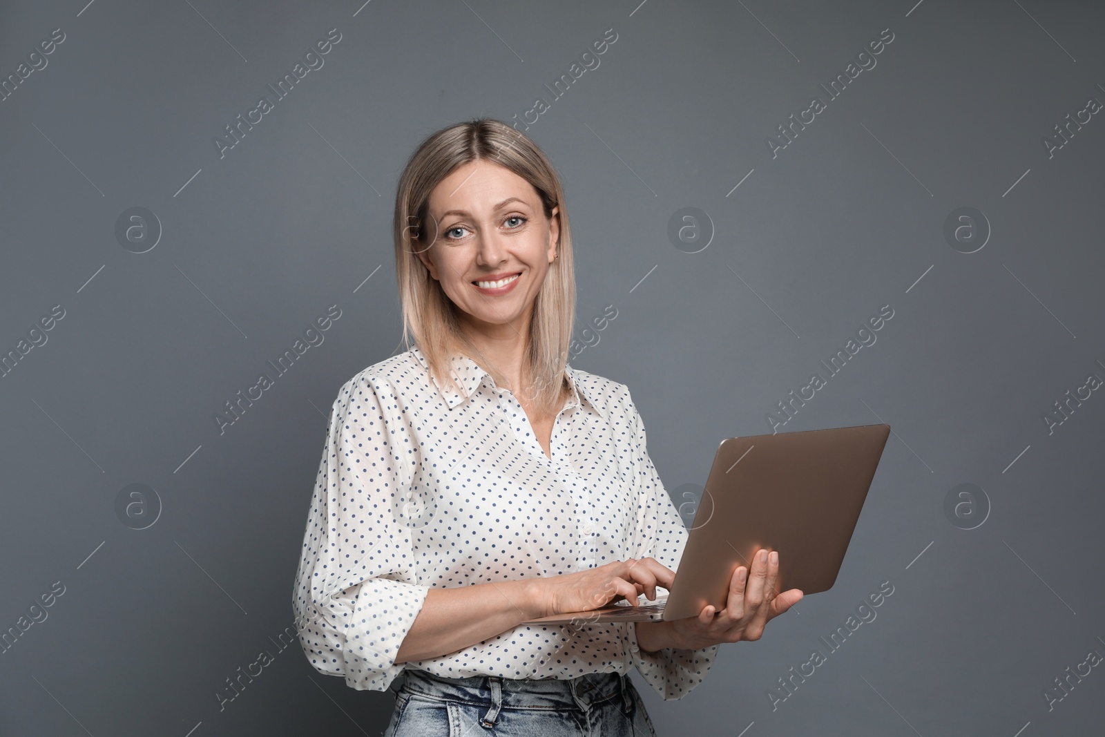 Photo of Beautiful woman with laptop on grey background