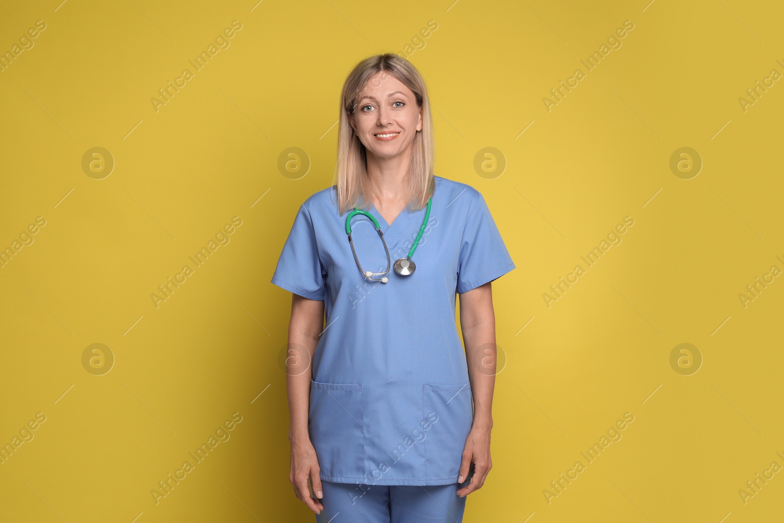 Photo of Portrait of nurse in medical uniform with stethoscope on yellow background