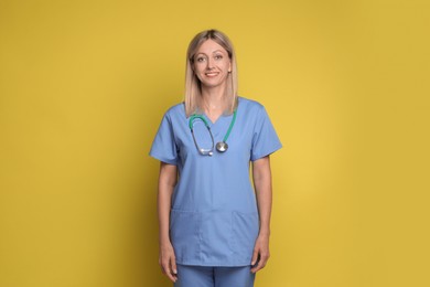 Portrait of nurse in medical uniform with stethoscope on yellow background