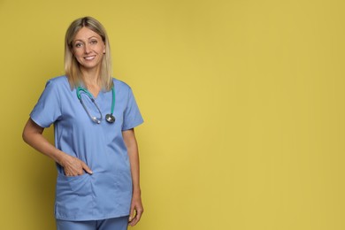 Portrait of nurse in medical uniform with stethoscope on yellow background, space for text