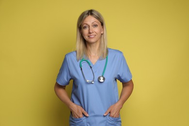 Portrait of nurse in medical uniform with stethoscope on yellow background