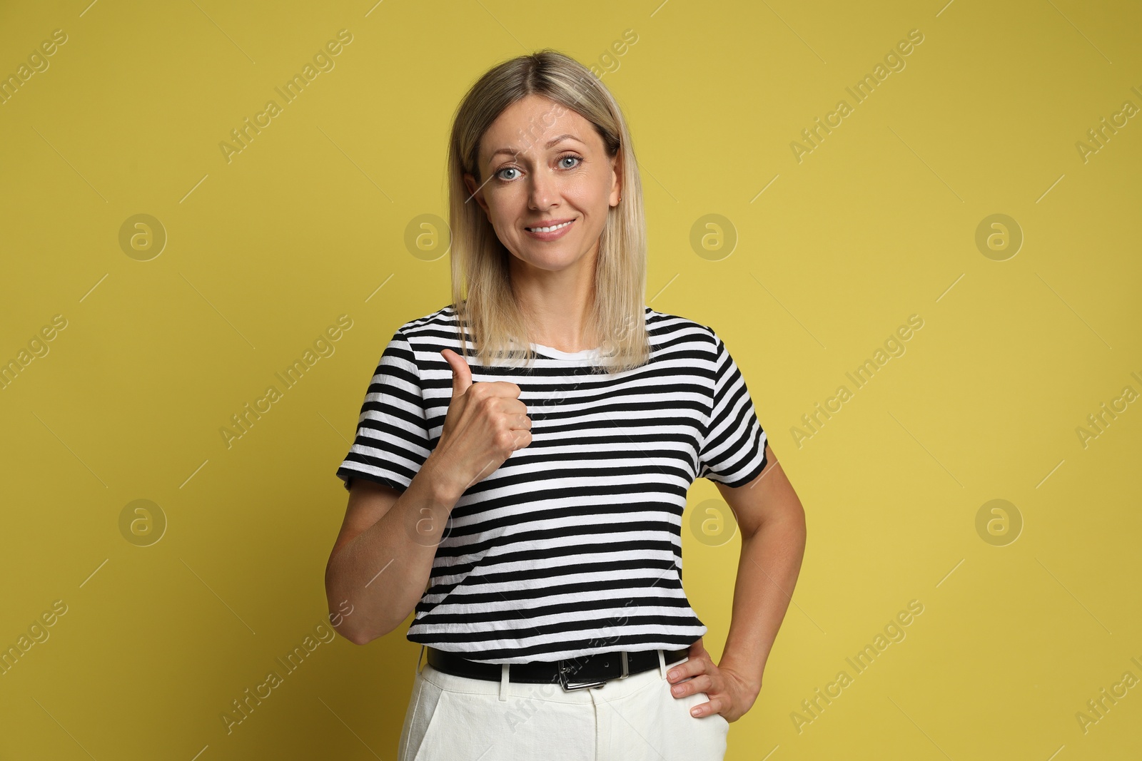 Photo of Beautiful woman showing thumbs up on yellow background