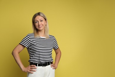 Portrait of beautiful smiling woman on yellow background, space for text