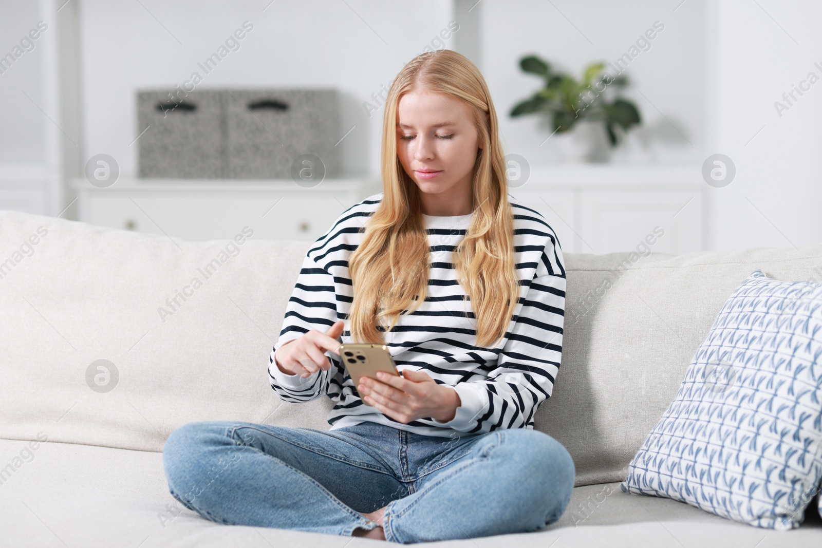 Photo of Beautiful woman using smartphone on sofa indoors