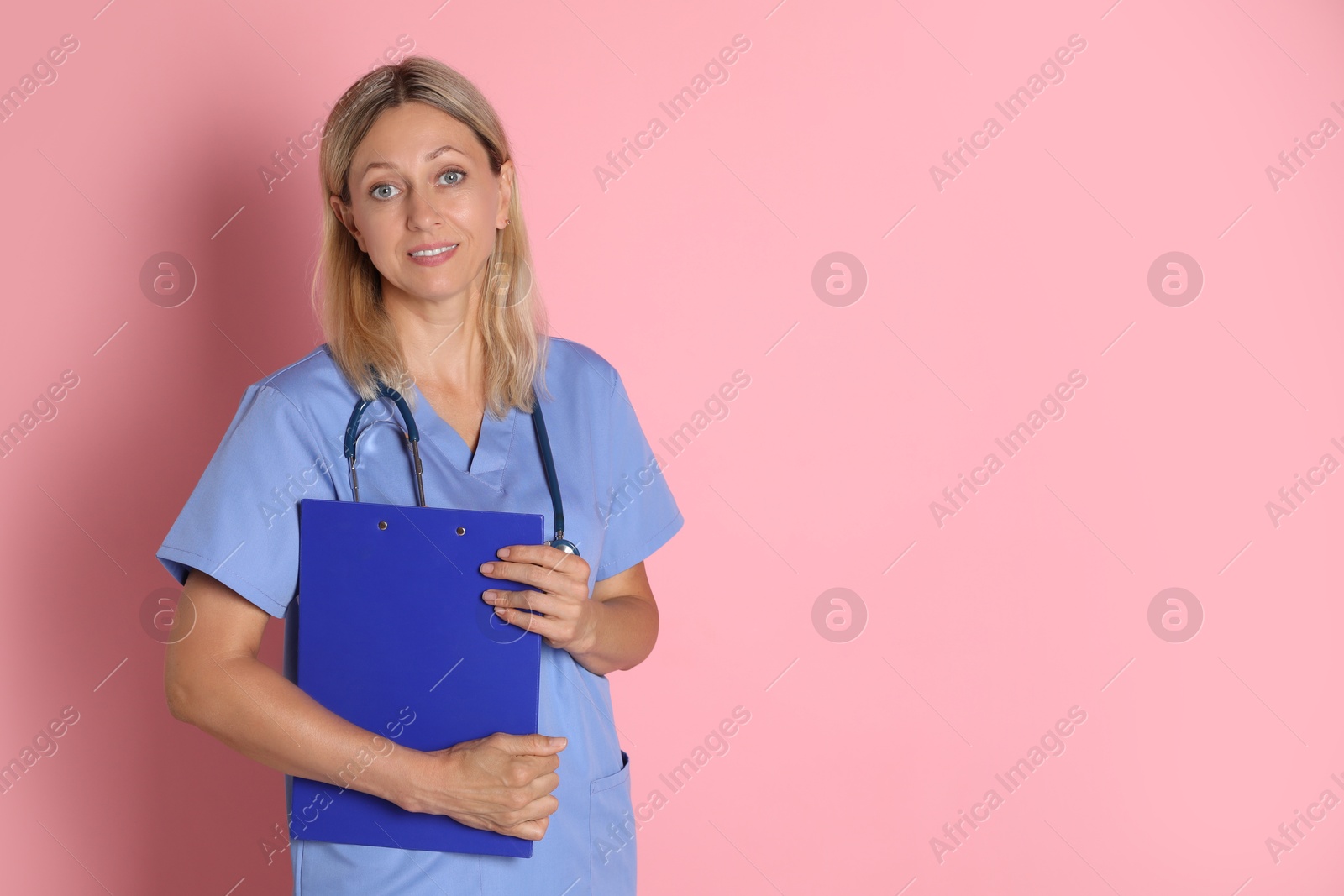 Photo of Portrait of doctor in medical uniform with stethoscope and clipboard on pink background, space for text