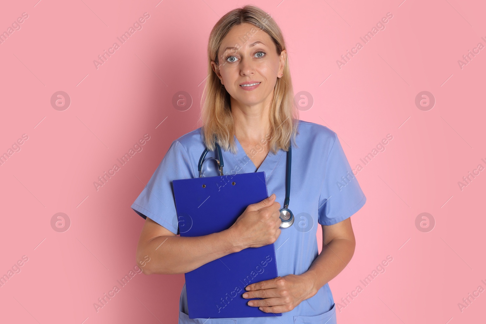 Photo of Portrait of doctor in medical uniform with stethoscope and clipboard on pink background