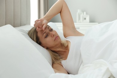 Menopause. Woman suffering from headache in bed at home