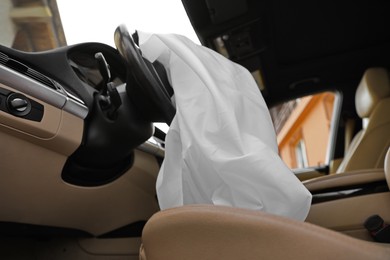 Photo of Opened airbag in automobile, closeup. Car safety equipment