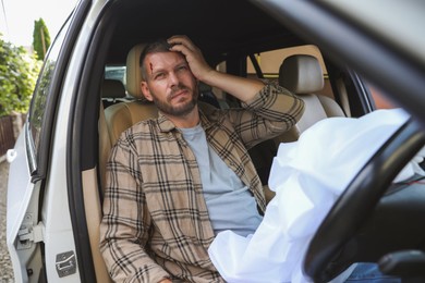 Photo of Injured man near opened airbag in automobile after car accident