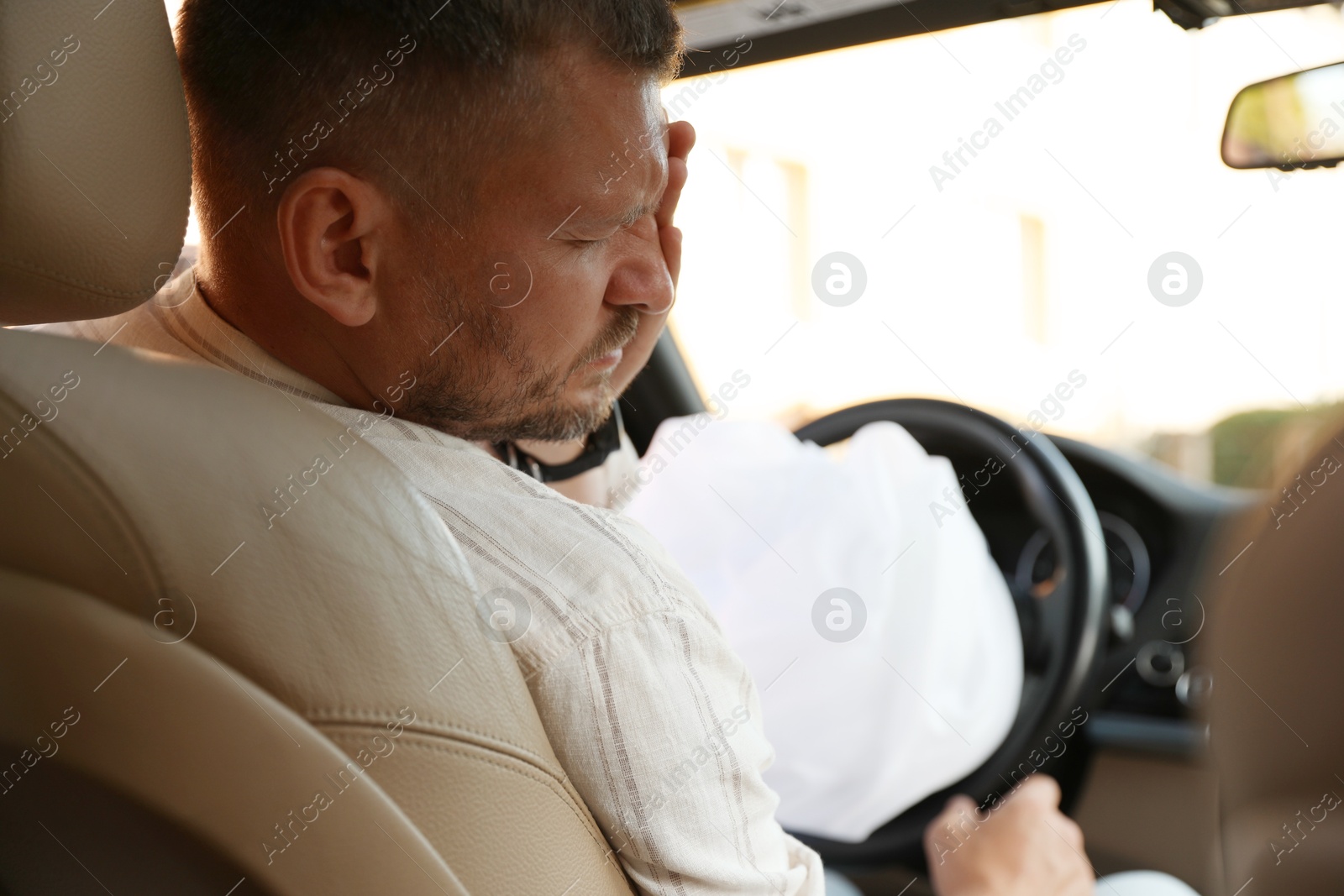 Photo of Injured man near opened airbag in automobile after car accident