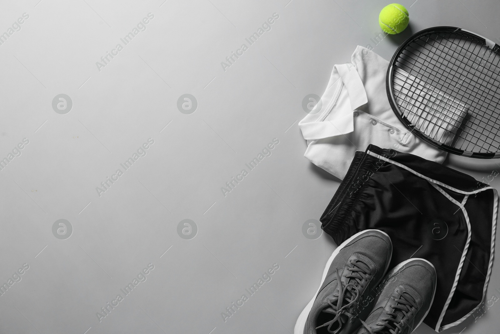 Photo of Tennis racket, balls and sportswear on light grey background, flat lay. Space for text