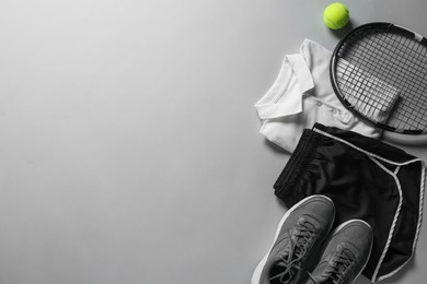 Photo of Tennis racket, balls and sportswear on light grey background, flat lay. Space for text