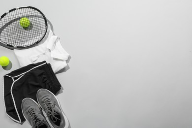 Photo of Tennis racket, balls and sportswear on light grey background, flat lay. Space for text