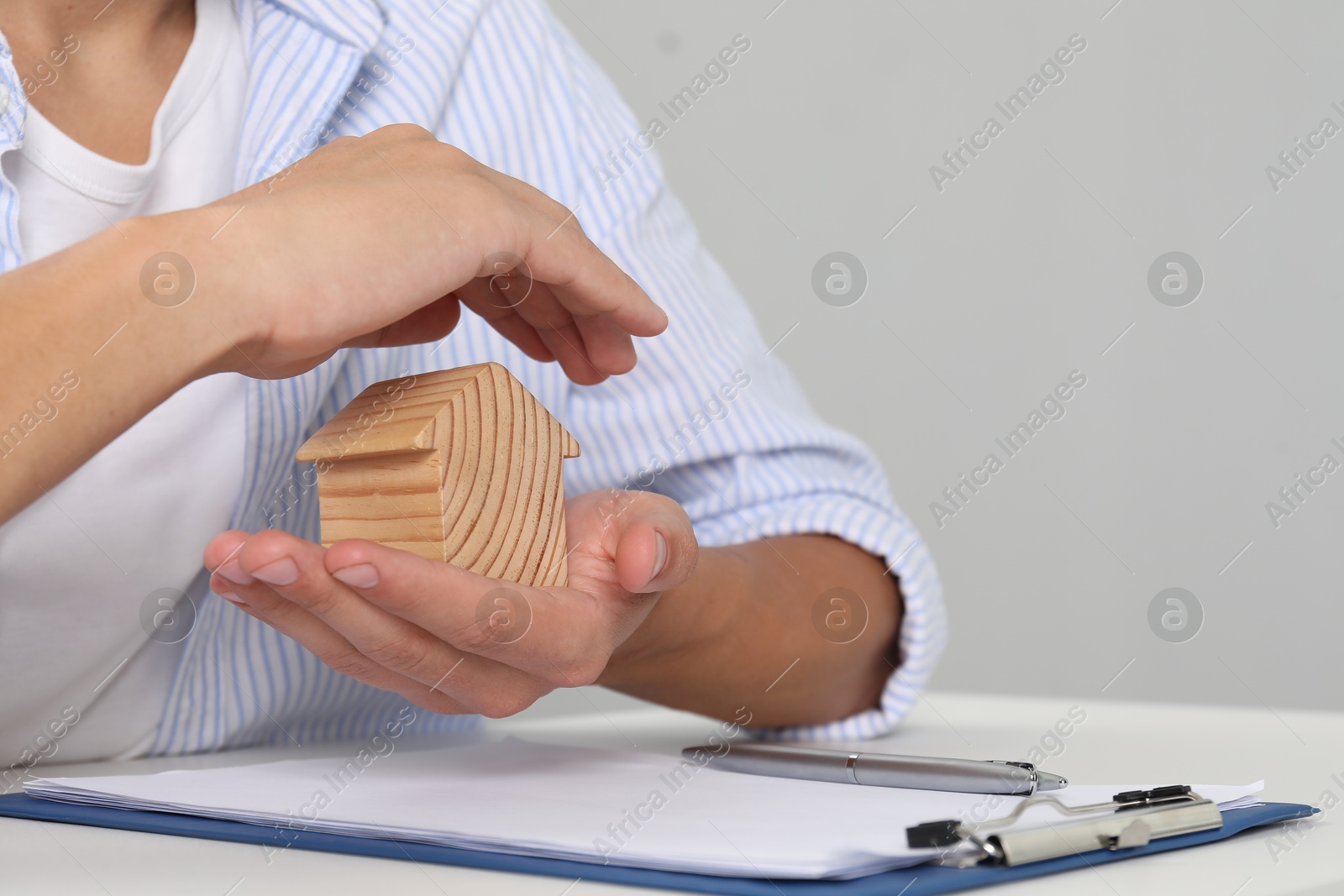 Photo of Real estate insurance. Man with wooden house figure at light table, closeup